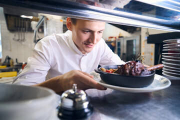 Young man has prepared lamb shank with vegetables for serving - obrazy, fototapety, plakaty