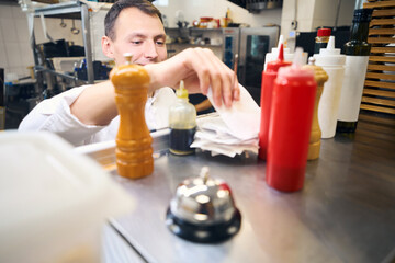 Young kitchen worker looks through sales receipts