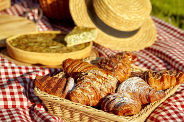 Wicker tray with sweet croissants on cozy summer picnic
