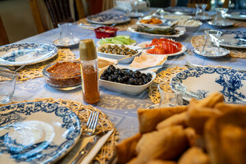 Cheese, green and black olives, honey, tomato, cucumber, pepper, breakfast sauce, fried pastry pastries on the family's table at home.