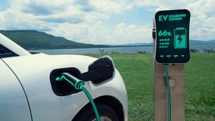  Electric car plugged in with charging station to recharge battery by EV charger cable with nature and lake background. Future innovative ev car and energy sustainability. Peruse © Summit Art Creations