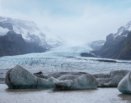 Glacier tongue slides from Vatnaj&ouml;kull icecap or Vatna Glacier near subglacial &Ouml;r&aelig;faj&ouml;kull volcano, Iceland. Glacial lagoon with ice blocks and surrounding mountains.