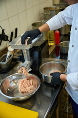 Kitchen staff grinds meat in a meat grinder