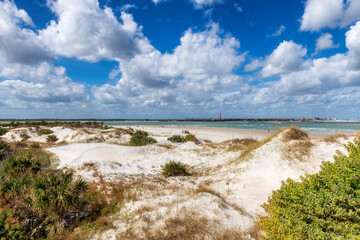 Fototapeta na wymiar Beach sand dunes in sunny day and Lighthouse Ponce de Leon Inlet in New Smyrna beach, Florida.