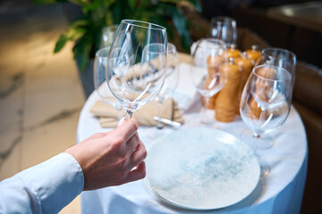 Waiter holds a large glass in his hands