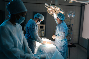 Surgeon in sterile gloves, surgical uniforms and masks adjusting light before operation in operating theatre. Surgery, hospital, medical and healthcare services. Concept of surgery and emergency.