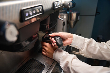 Barista in a white blouse prepares coffee in coffee machine