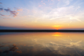 Reflection of the sunset in the water. Beautiful sunset over the sea. Colored sky at sunset.