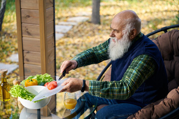 Elderly man is chopping vegetables for a salad