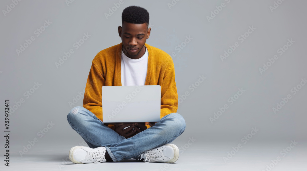 Canvas Prints a person is sitting cross-legged on the floor, focused on working with a laptop.