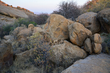 Rocky arid terrain with large boulders between rocky hills under a blue sky