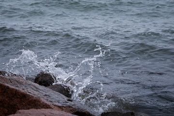Close-up of splash of a small wave crashing on rocks.