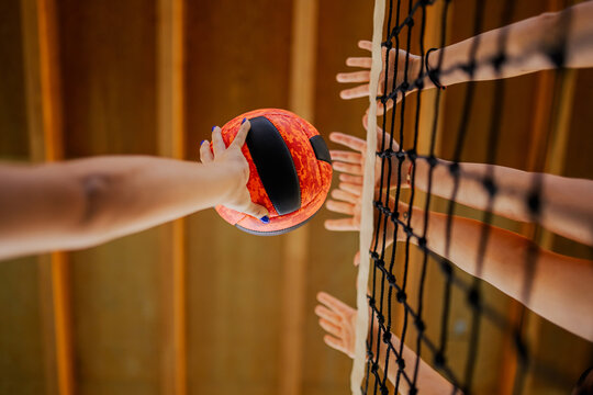 Close up of volleyball players' hands blocking a ball over net.