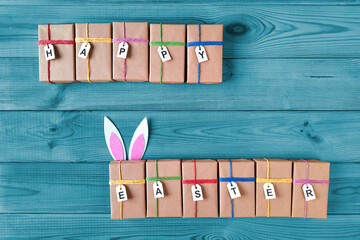 Easter gifts. Boxes with gifts and the inscription Happy Easter on a blue wooden table. Preparation...
