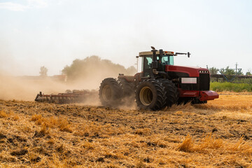 A tractor with a plow plows the field after harvesting.