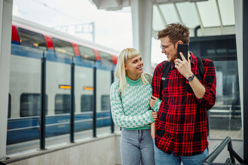 Young hipster couple is walking together at train station in metropolis.