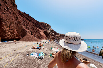 Woman with white hat observes the Red Beach (Kokkini Paralia). Greek Islands, Santorini, Tourism, Traveling