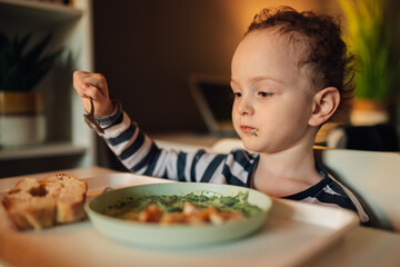 Portrait of a child using spoon for eating homemade lunch.