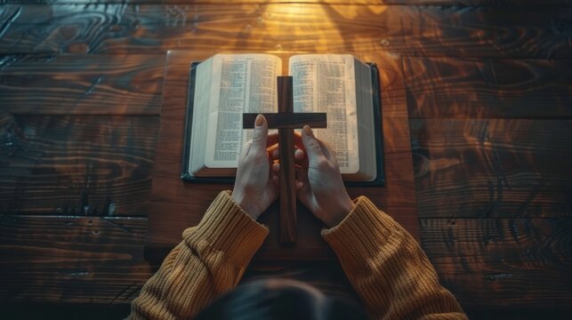 A woman who believes in a higher power is pictured holding a wooden cross on an open holy bible placed