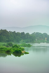 Fototapeta na wymiar A landscape view of a calm river with green trees and mountain in India
