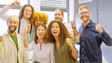 Coworkers celebrating raising fist and looking at camera