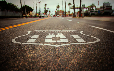 Highway 101 sign painted on the black asphalt road with city diffused in the background. The shot...