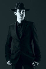 portrait of a young man in a suit with a hat, shot in the studio in black and white