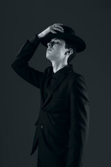 portrait of a young man in a suit with a hat, shot in the studio in black and white