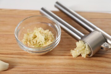 Garlic press and mince on wooden table, closeup