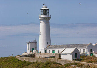 Tall white stone lighthouse at the edge of the cliffs on a rugged coastline. South Stack Lighthouse, Holy Island Anglesey, North Wales