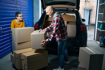 Bald guy takes boxes of things out of the car