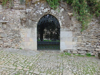Puerta de hierro en la entrada de una antigua pared de piedra, en Santillana del mar, Cantabria