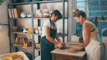 Woman, teamwork and clay for pottery, small business or molding art together at workshop. Female person and colleague smile in store for creation, creativity or startup with mold of ceramics indoors - Powered by Adobe
