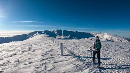 Woman in snowshoes on the way to majestic summit peak Grosser Speikogel in Kor Alps, Lavanttal Alps, Carinthia Styria, Austria. Winter wonderland in Austrian Alps. Idyllic ski touring hiking trail