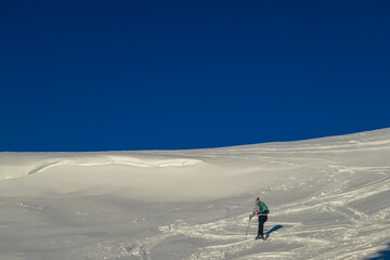 Woman in snowshoes on snow covered mountains of Kor Alps, Lavanttal Alps, Carinthia Styria, Austria. Winter wonderland in Austrian Alps. Ski touring and snow shoe tourism. Tranquil serene atmosphere