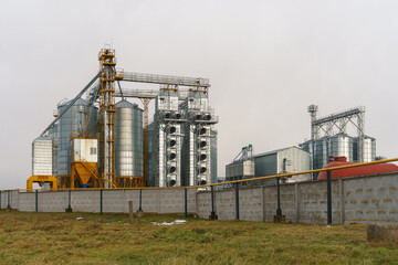 Obraz premium silver silos on agro manufacturing plant for processing drying cleaning and storage of agricultural products, flour, cereals and grain. Large iron barrels of grain. Granary elevator