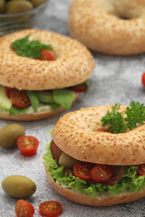 Sesame bagels with tomatoes, ham and olives