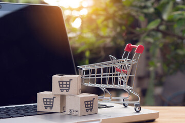 Shopping online. cardboard box with a shopping cart logo and empty trolley on laptop keyboard....