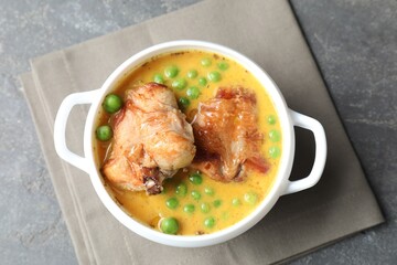 Tasty cooked rabbit meat with sauce and peas on grey table, top view