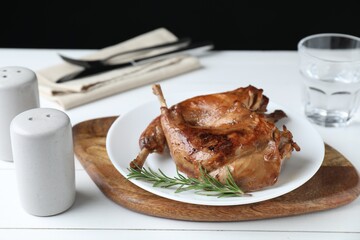 Tasty cooked rabbit meat with rosemary on white wooden table