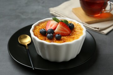 Delicious creme brulee with berries and mint in bowl on grey table, closeup
