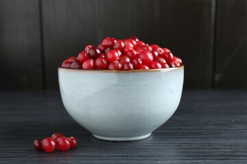 Cranberries in bowl on black wooden table, closeup