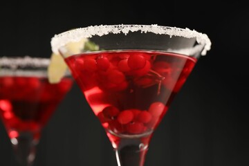 Tasty cranberry cocktail in glasses against black background, closeup
