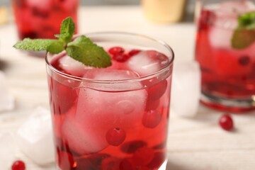 Tasty cranberry cocktail with ice cubes in glass on table, closeup