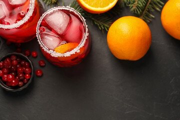 Tasty cranberry cocktail with ice cubes in glasses on dark gray table, flat lay. Space for text
