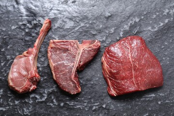 Fresh raw beef cuts on grey textured table, flat lay