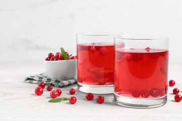 Tasty cranberry juice in glasses and fresh berries on white wooden table. Space for text