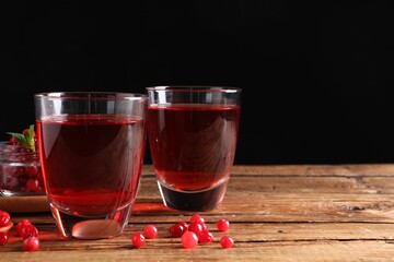 Tasty cranberry juice in glasses and fresh berries on wooden table. Space for text