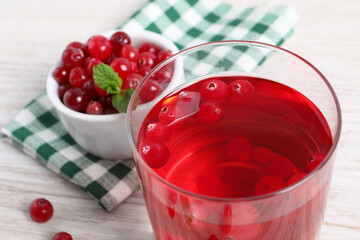 Tasty cranberry juice in glass and fresh berries on white wooden table, closeup