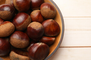 Sweet fresh edible chestnuts on light wooden table, top view. Space for text
